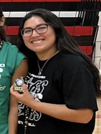 two girls are posing for a photo with a volleyball trophy