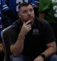 a man sitting on the sidelines watching a football game